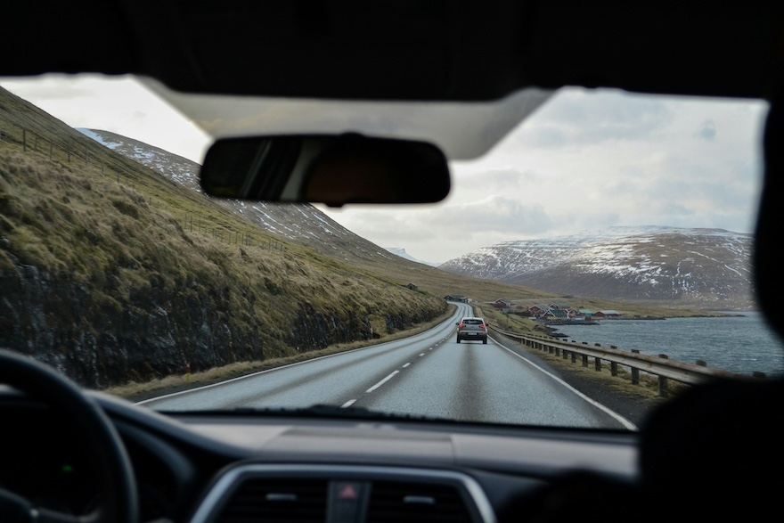 Vehicle driving down highway with snow covered mountains in distance